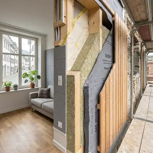 Mur en construction avec isolation en laine de roche et revêtement en bois.